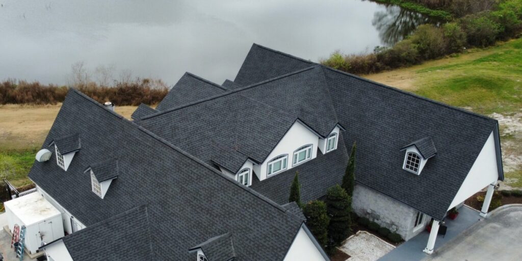 Completed large roof with dark gray architectural shingles and several dormers